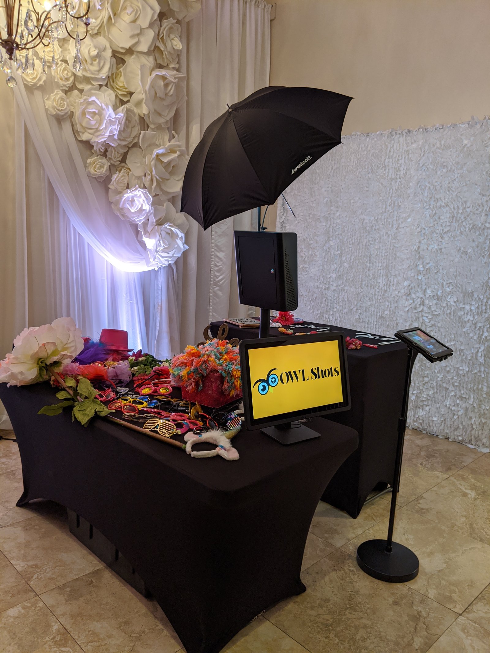 OWLShots touchscreen photo booth set up at a wedding reception, framed by floral decor