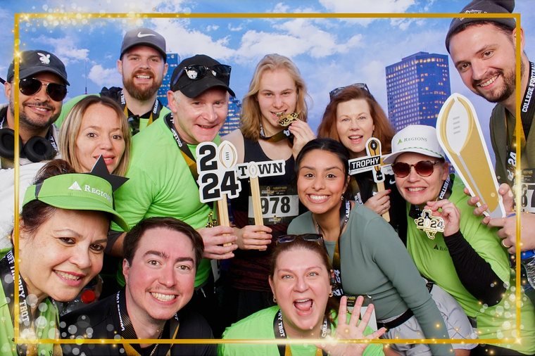 Runners posing with trophy props at the Houston College Football Playoff Trophy Trot, sponsored by Regions Bank